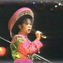 Woman dressed in bright Asian clothing singing.